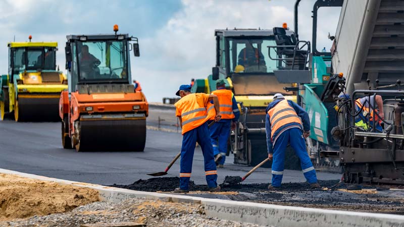 Road construction with workers and steam rollers