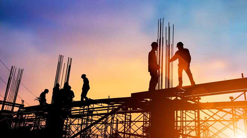 Silhouette of construction workers on large project